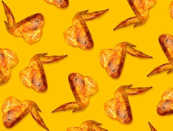 A seamless pattern of roasted chicken wings arranged on a bright yellow background.