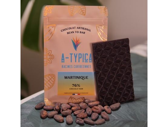 “A-Typica” artisanal chocolate pouch (Martinique, 76% dark chocolate) with a chocolate bar and cocoa beans in front.