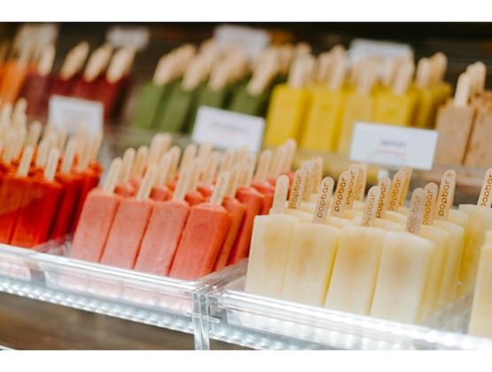 Refrigerated display filled with colorful ice pops arranged in rows, featuring various flavors in red, green, yellow, and white tones.