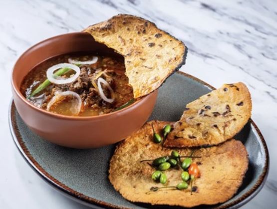 Bol de soupe riche garni d’oignons et d’herbes, servi avec des tranches de pain grillé sur une assiette en céramique.