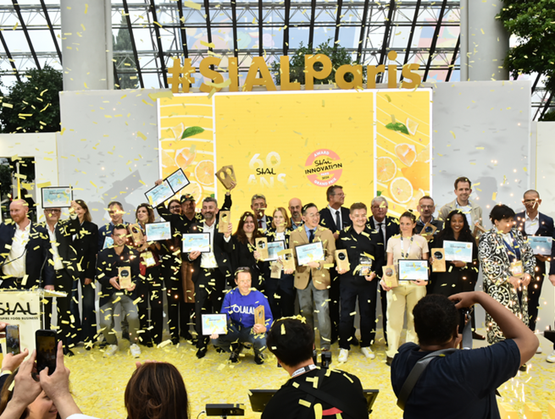 Cérémonie de remise de prix au SIAL Paris avec des lauréats sur scène tenant leurs trophées et certificats, sous une pluie de confettis devant un public.