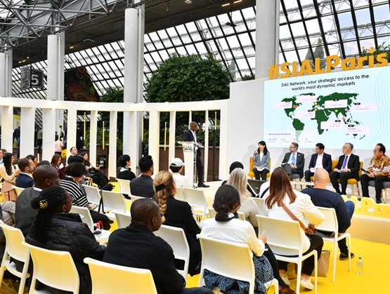 Table ronde SIAL Paris avec plusieurs intervenants sur scène et un public assis, autour d’une présentation sur les marchés internationaux dans un espace lumineux.