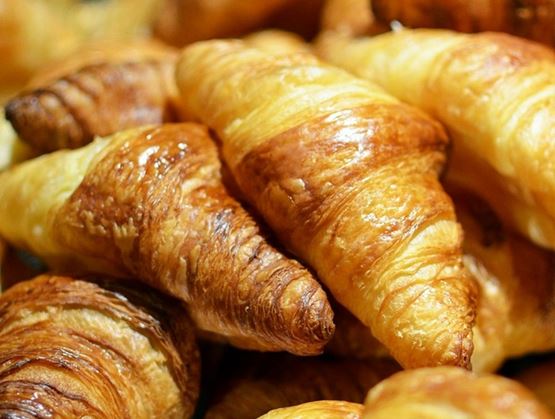 Assortiment de croissants dorés et feuilletés empilés, mettant en valeur leur texture croustillante et brillante.
