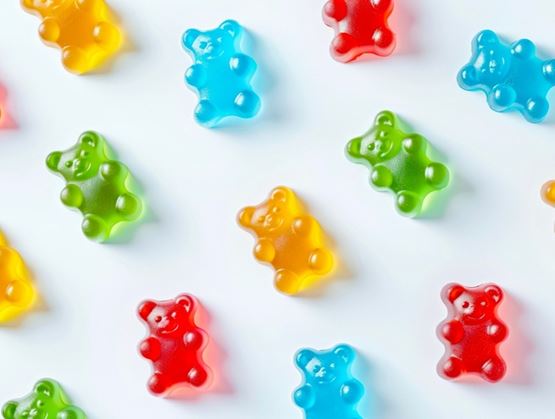 Assortiment de bonbons gélifiés en forme d’oursons colorés disposés sur un fond clair.