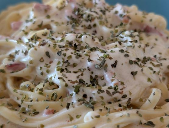 Close-up of pasta with creamy sauce topped with aromatic herbs.