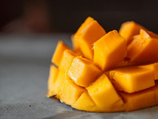 Gros plan sur une mangue mûre coupée en cubes, présentée dans sa peau, avec une texture juteuse et une couleur orange vive.