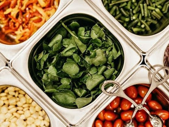 Bacs d’ingrédients variés contenant des tomates cerises, des haricots verts, des herbes fraîches et d’autres légumes.