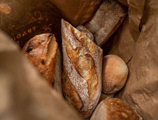 Pains artisanaux croustillants rangés dans un sac en papier brun.