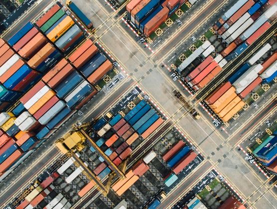 Vue aérienne d’un terminal portuaire avec des conteneurs colorés, des routes et des engins de manutention.