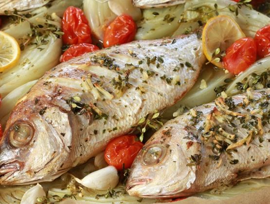 Poissons entiers cuits au four avec des tomates, du fenouil, du citron, de l’ail et des herbes aromatiques.