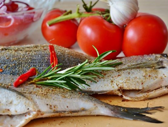 Poissons crus assaisonnés avec du romarin et du piment, accompagnés de tomates, d’ail et d’oignons rouges.