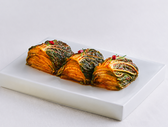Portions de kimchi de chou nappées de sauce épicée, servies sur une assiette blanche.