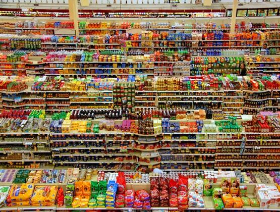 Vue d’ensemble de rayons de supermarché très fournis, remplis de produits alimentaires et de boissons aux emballages colorés.