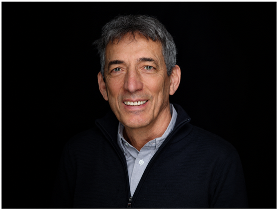 Portrait de Xavier Terlet souriant sur fond noir.