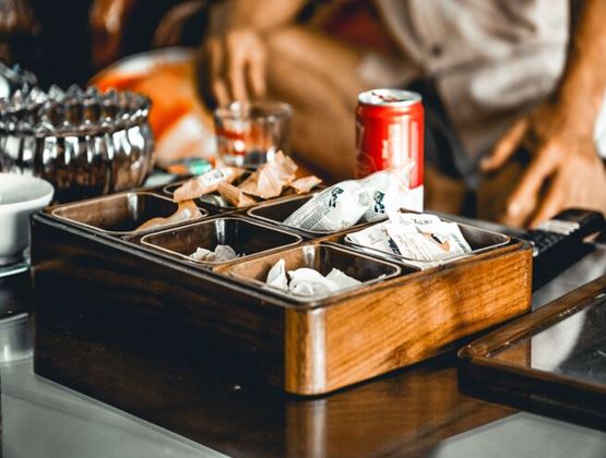 Sélection de snacks emballés individuellement présentés dans un plateau en bois dans un établissement hôtelier.