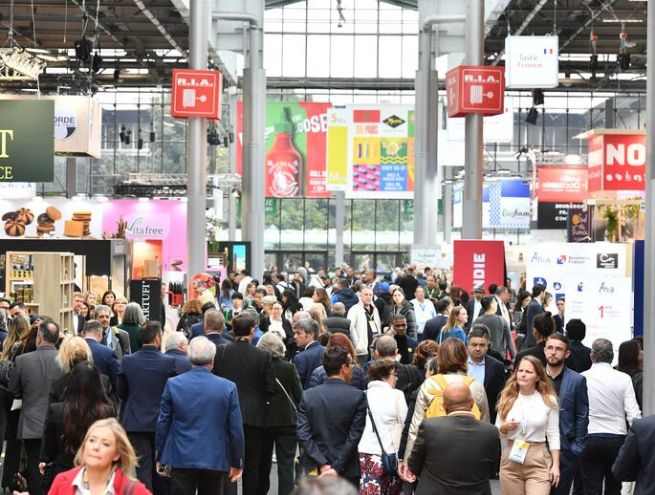 Allée principale d’un salon professionnel animée, remplie de visiteurs et d’exposants.