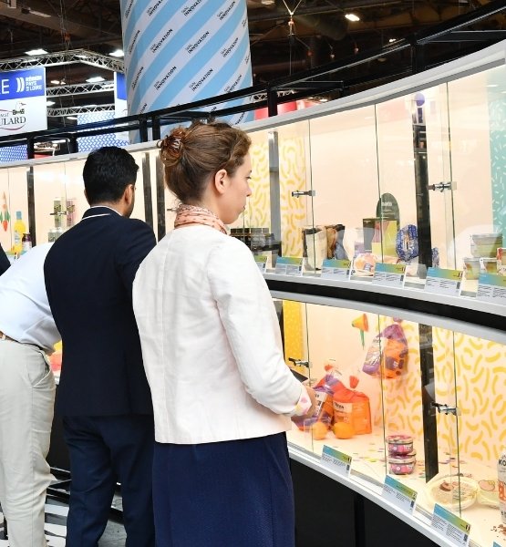 Visiteurs consultant des produits presentes dans une vitrine sur un salon professionnel.