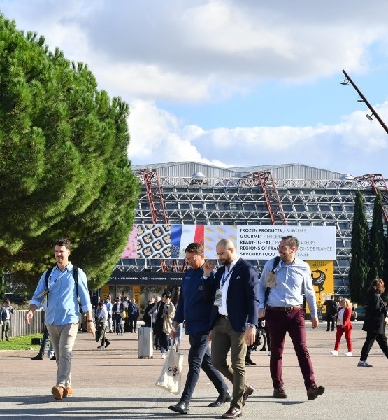 Visitors walking outside the exhibition center entrance during a trade show.