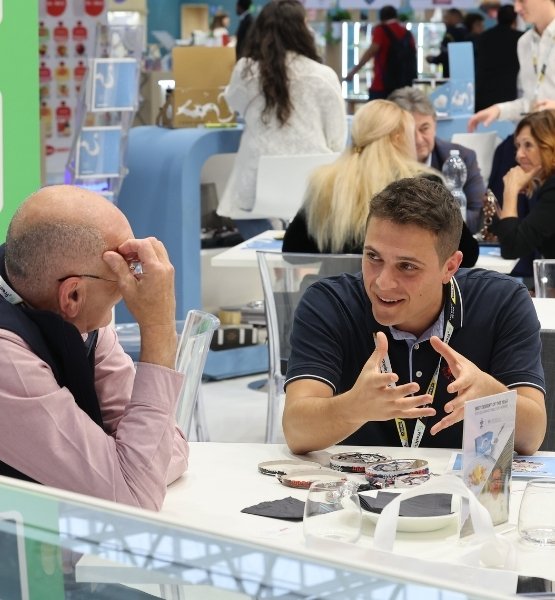 Deux professionnels discutent à une table sur un salon, dans un espace de rendez-vous B2B.