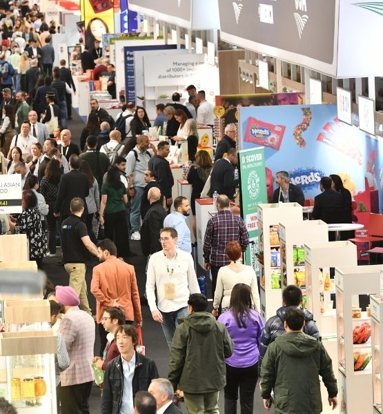 High-angle view of a busy trade show aisle with booths and many visitors.