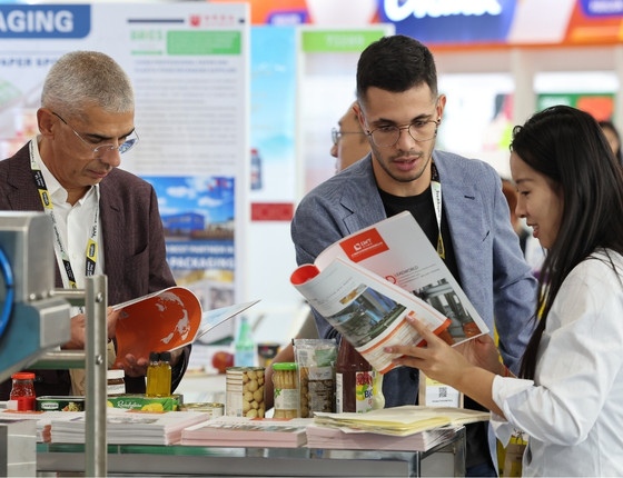 Lecture de brochure produit sur un stand d’exposition avec bocaux et emballages en présentation.