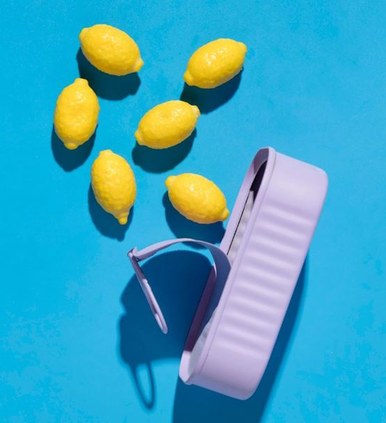 Yellow lemons and lilac grater on blue background
