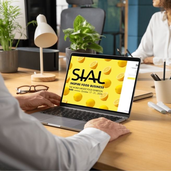 Person working on a laptop with the SIAL Paris 2026 'Inspire Food Business' event display.