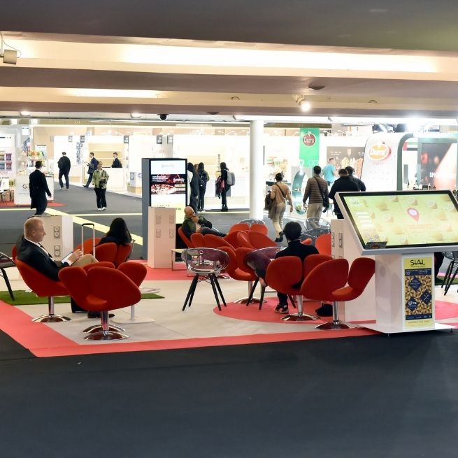 Exhibition space at SIAL Paris with red chairs and an interactive table displaying the event map.