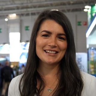 Portrait souriant de Madelaine Kastberg, devant des stands lumineux dans un salon professionnel.