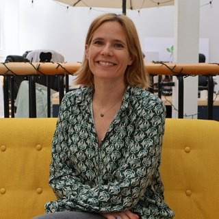 Smiling woman sitting on a yellow sofa in a bright workspace