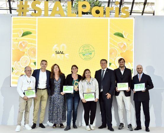 Group of award winners on stage at SIAL Paris holding certificates in front of yellow #SIALParis backdrop.