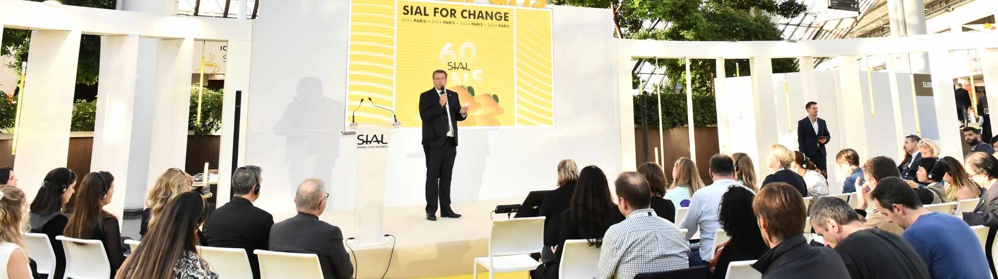SIAL for Change conference with speaker on stage facing seated audience.