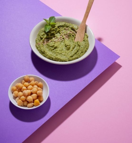 Bol de houmous accompagné de pois chiches, présenté sur fond graphique coloré