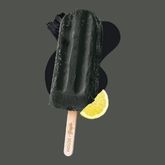 Glace à l’eau noire en forme de bâtonnet, accompagnée d’un quartier de citron