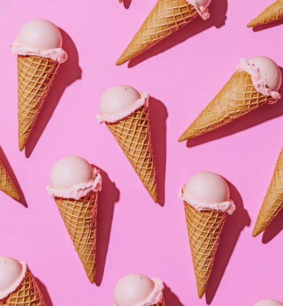Cornets de glace à la vanille et à la fraise disposés en motif sur fond rose