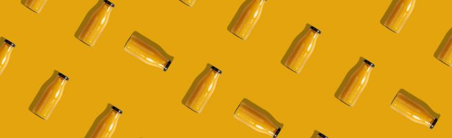Repeating pattern of orange juice bottles arranged diagonally on a yellow background.