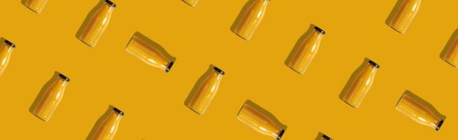 Repeating pattern of orange juice bottles arranged diagonally on a yellow background.