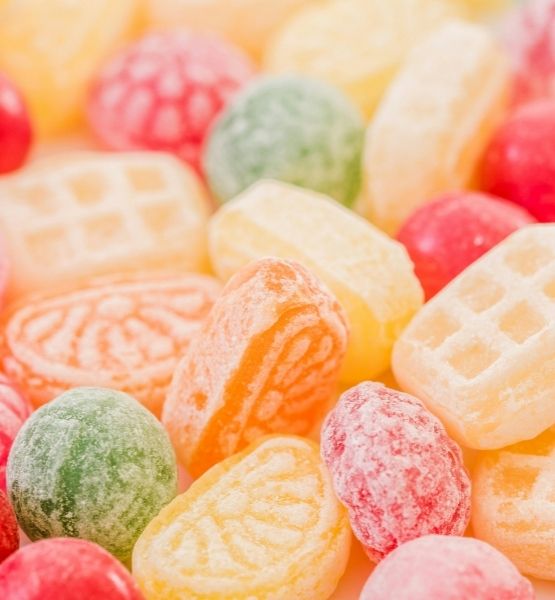 Colorful sugar-free candies in various shapes, arranged on a blurred background.