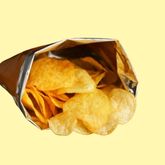 Open bag of potato chips with golden crisps visible against a yellow background.
