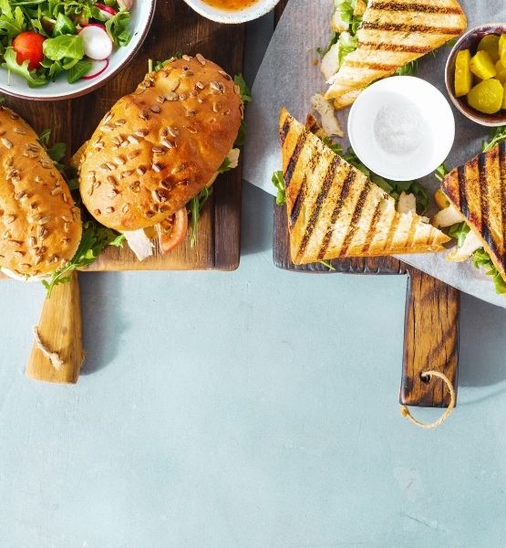 Sandwich toasté avec salade et pickles servis sur une planche en bois