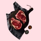 Rib-eye steaks on dark board