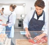 A man cutting up a piece of red meat
