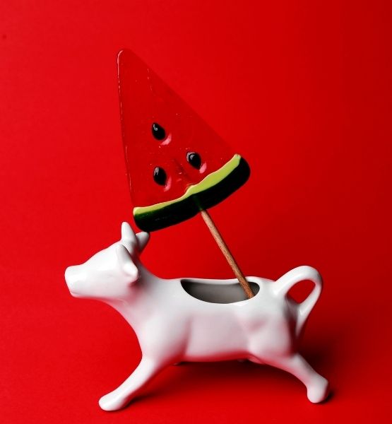 Objet décoratif en forme de bœuf blanc avec une sucette pastèque plantée sur fond rouge