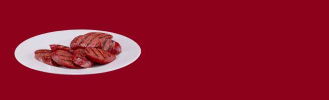 Saucisses grillées présentées sur une assiette blanche sur fond rouge