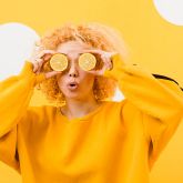 Personne portant un sweat jaune et utilisant des tranches de citron comme lunettes, sur fond jaune.