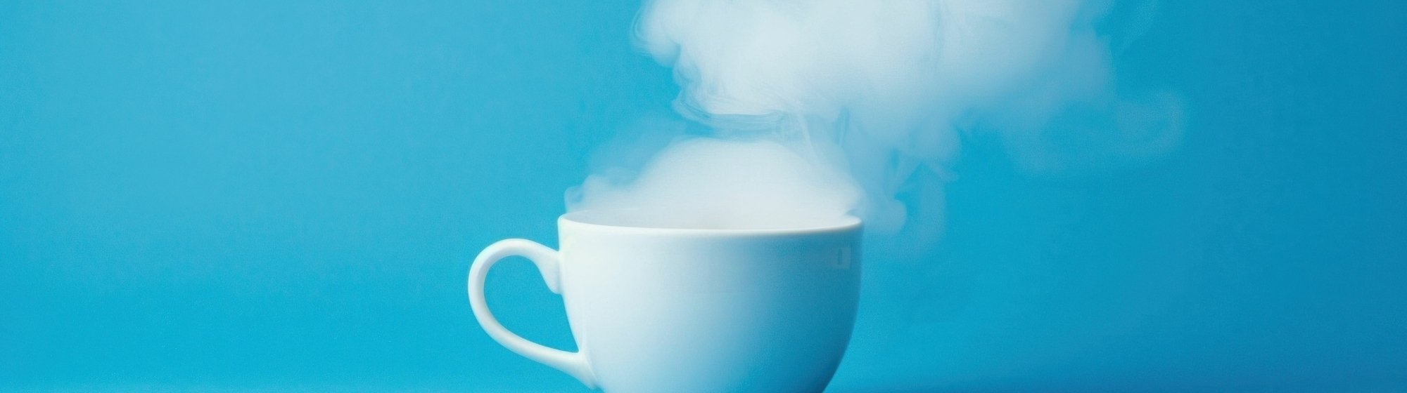 Tasse blanche dont s’échappe de la vapeur, sur fond bleu, ambiance minimaliste.