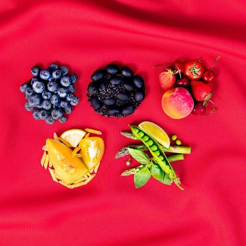 Arrangement of fruits and vegetables representing the Olympic rings on a bright red background.