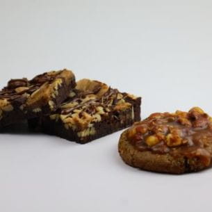 Deux desserts végétaux présentés sur une surface blanche : un brownie aux noix et un biscuit nappé de fruits secs.