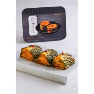Sliced kimchi arranged on a white plate, with elegant packaging in the background.