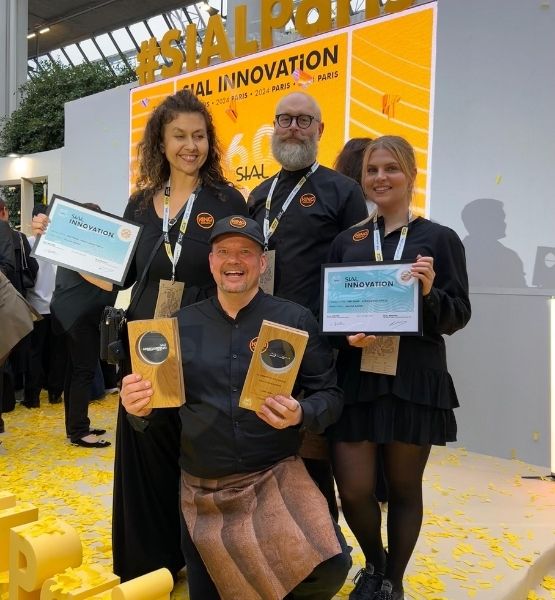 Group of smiling people holding SIAL awards in a festive setting.